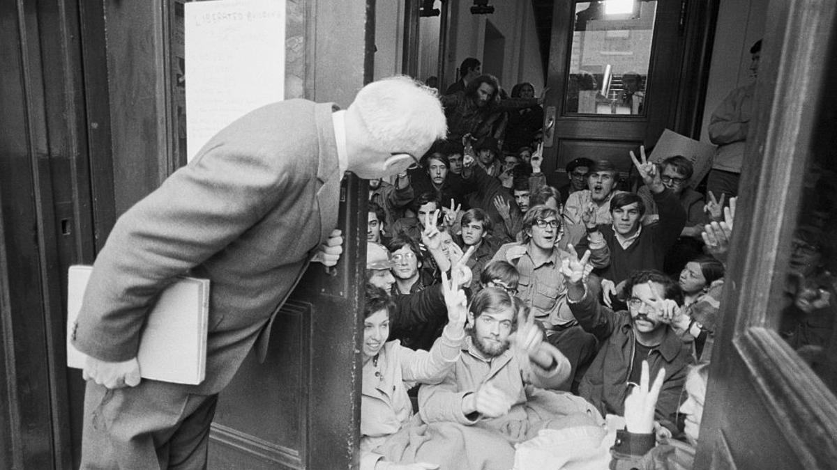 Un profesor se asoma desde una entrada bloqueada por una sentada de estudiantes en la Universidad de Columbia en abril de 1968