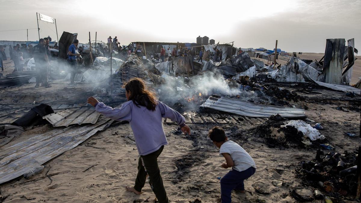 Palestinos entre los daños en el campo de desplazados de Rafah atacado por Israel este 27 de mayo