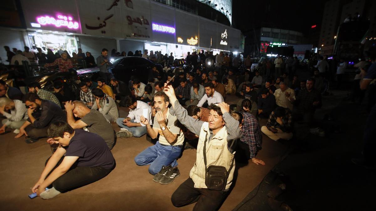 Un grupo de personas reza por el presidente de Irán, Ebrahim Raisi, en una de las calles del centro de Teherán.