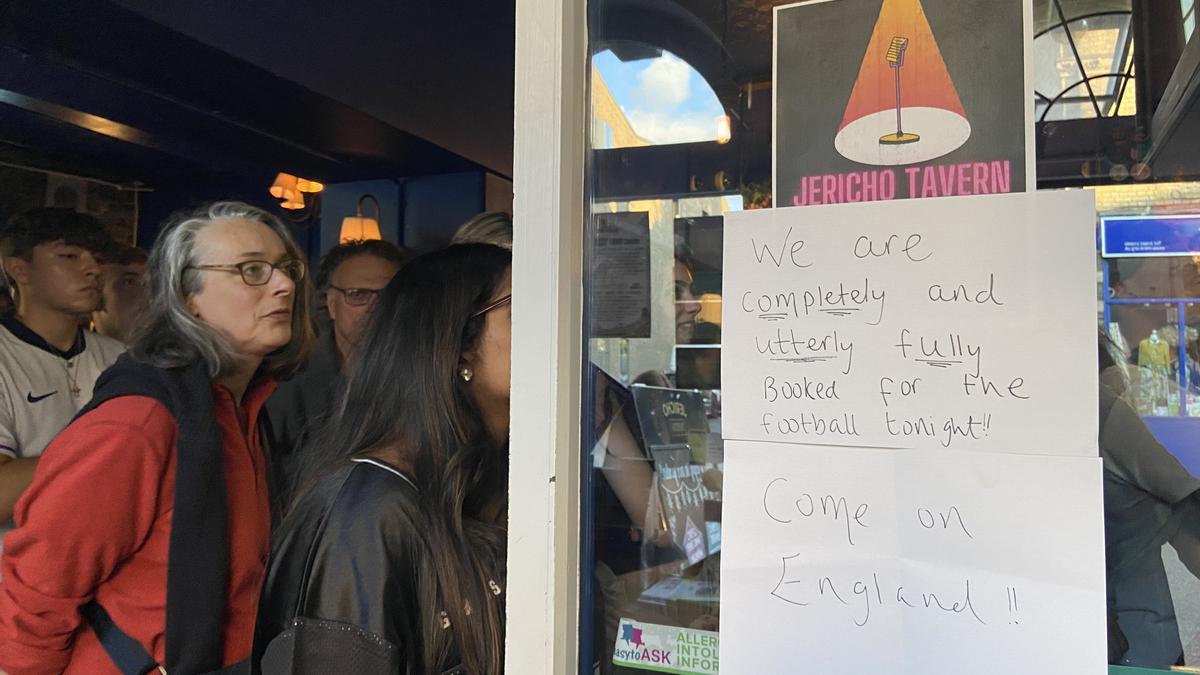 Aficionados ven la final Inglaterra-España junto a un cartel que dice que el pub está "completa, total y absolutamente" lleno