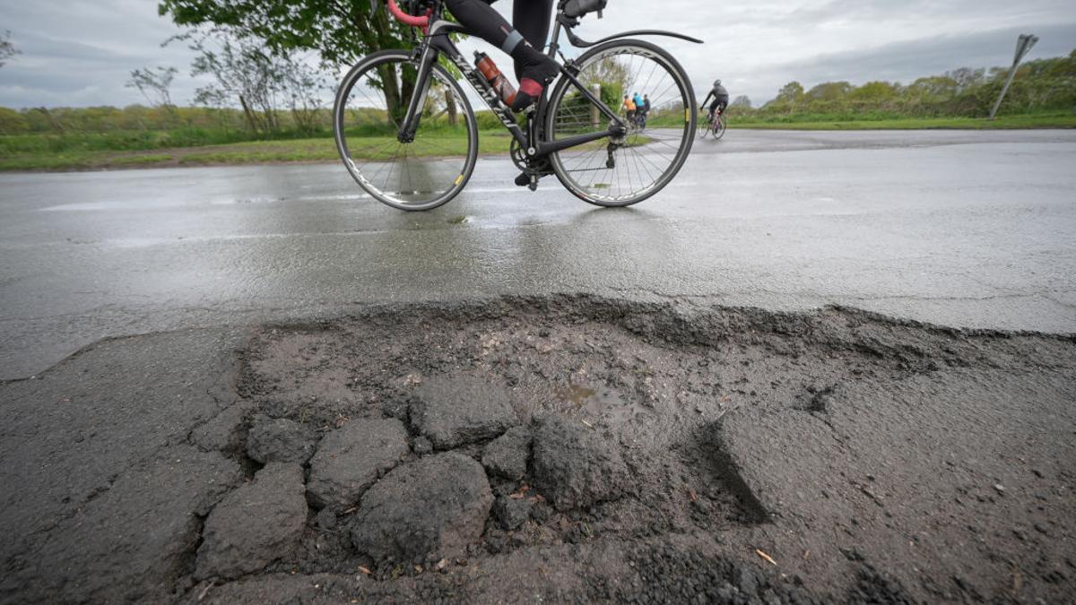 Un ciclista pasa junto a un bache en una calle en Northwich, Inglaterra, el 25 de abril de 2024.