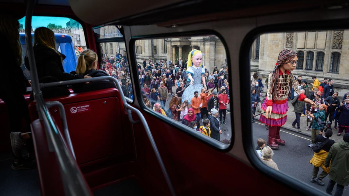 Un grupo de turistas observa desde un autobús de dos pisos el desfile de 'Alicia en el país de las maravillas' en la calle principal de Oxford.