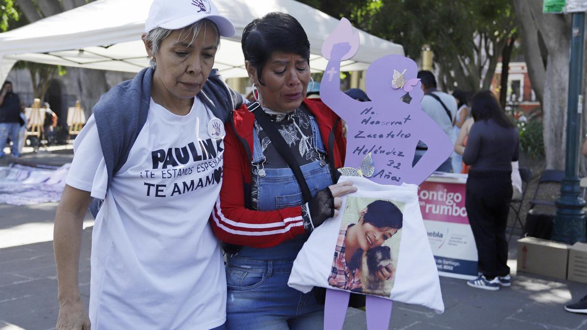 Dos mujeres ponen una camiseta a una silueta de madera durante un evento conmemorativo a personas desaparecidas, este domingo en el estado de Puebla (México). Con lágrimas en los ojos, los asistentes recordaron a sus víctimas de desaparición o feminicidio, dejaron todo el dolor en cada letra plasmada, alentadas por otras mujeres con el mismo dolor, con el objetivo de mantenerse fuertes y firmes en una lucha hasta el momento sin respuestas.