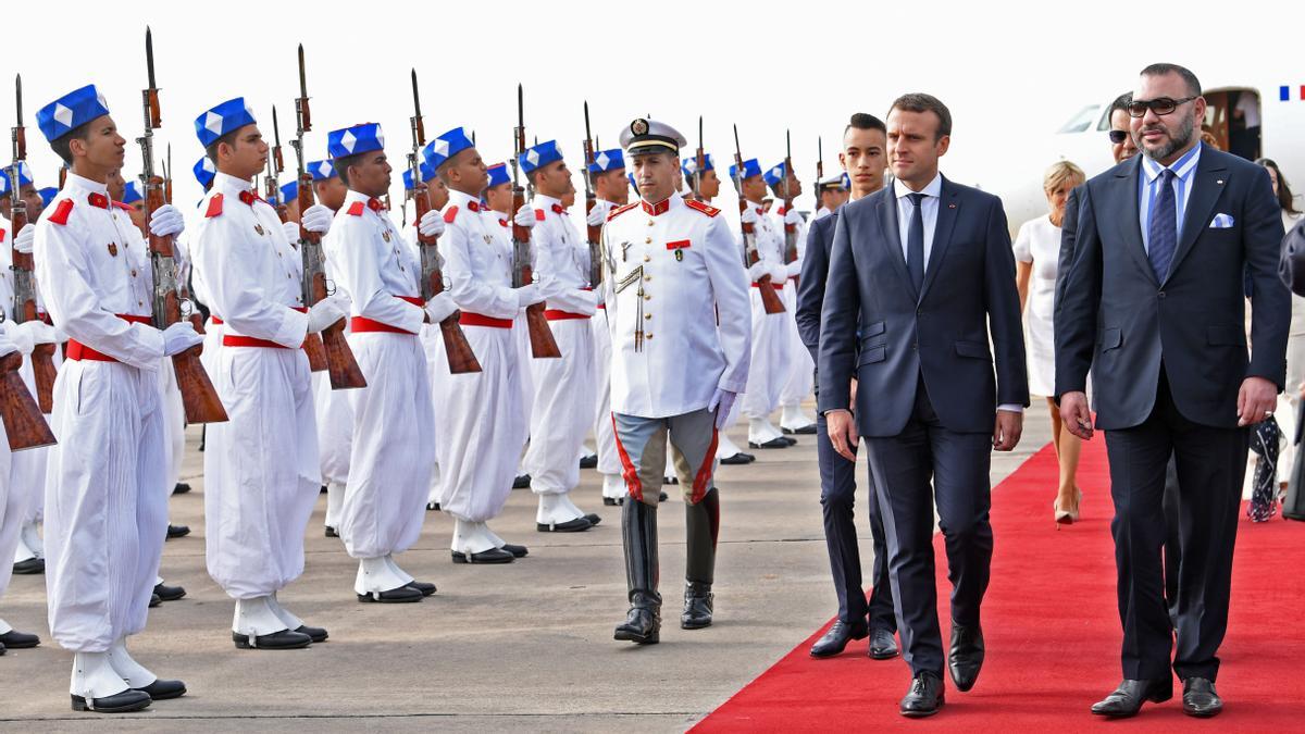 El rey marroquí Mohammed VI camina junto al presidente francés Emmanuel Macron mientras pasan revista a la guardia de honor a la llegada de este último a Rabat el 14 de junio de 2017. Macron se encuentra de visita oficial en Marruecos.