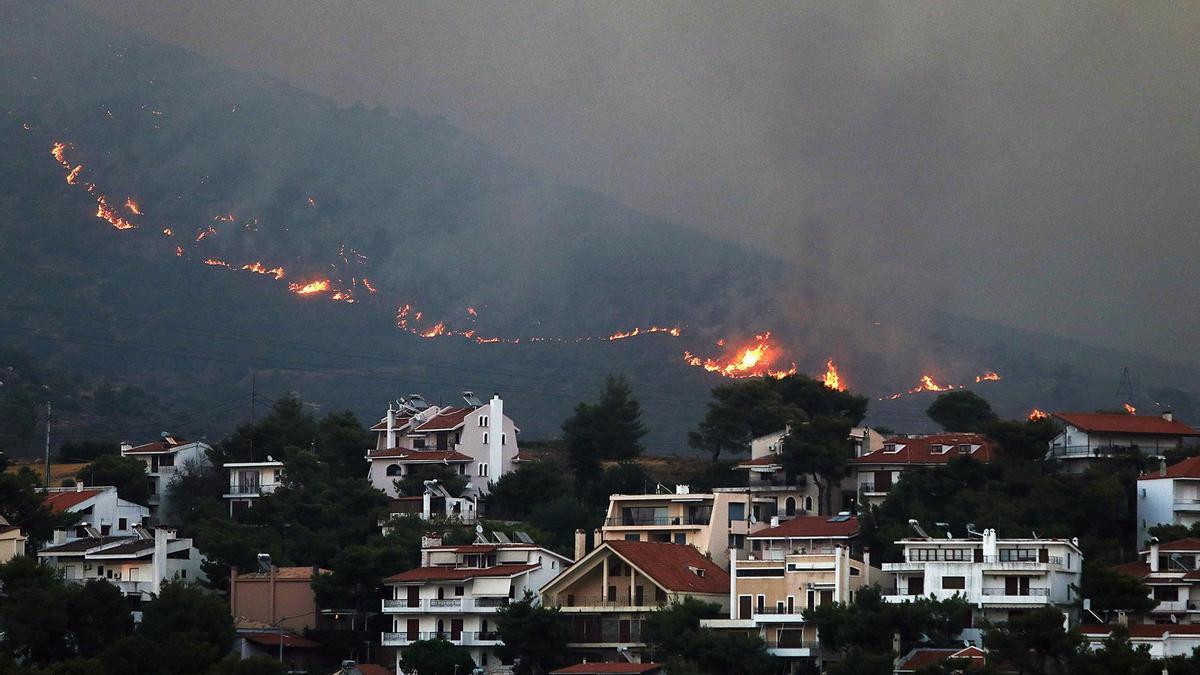 Un incendio se acerca a las casas en el monte Penteli, en el noreste de Grecia, este lunes.