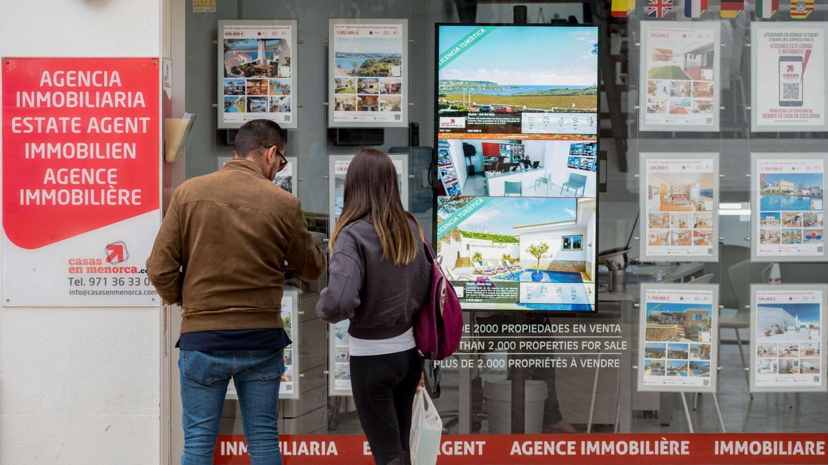 Imagen de archivo de una pareja observando las propiedades en venta anunciadas en el escaparate de una agencia inmobiliaria. EFE/ David Arquimbau Sintes