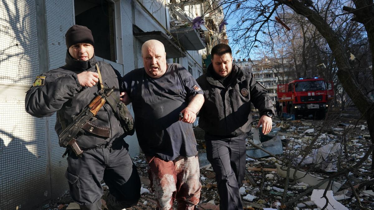 CHUHUIV, UCRANIA. Fuerzas de seguridad ucranianas acompañan a un hombre herido después de que un ataque aéreo alcanzara un complejo de apartamentos en Chuhuiv, en el óblast de Kharkiv, Ucrania, el 24 de febrero de 2022.