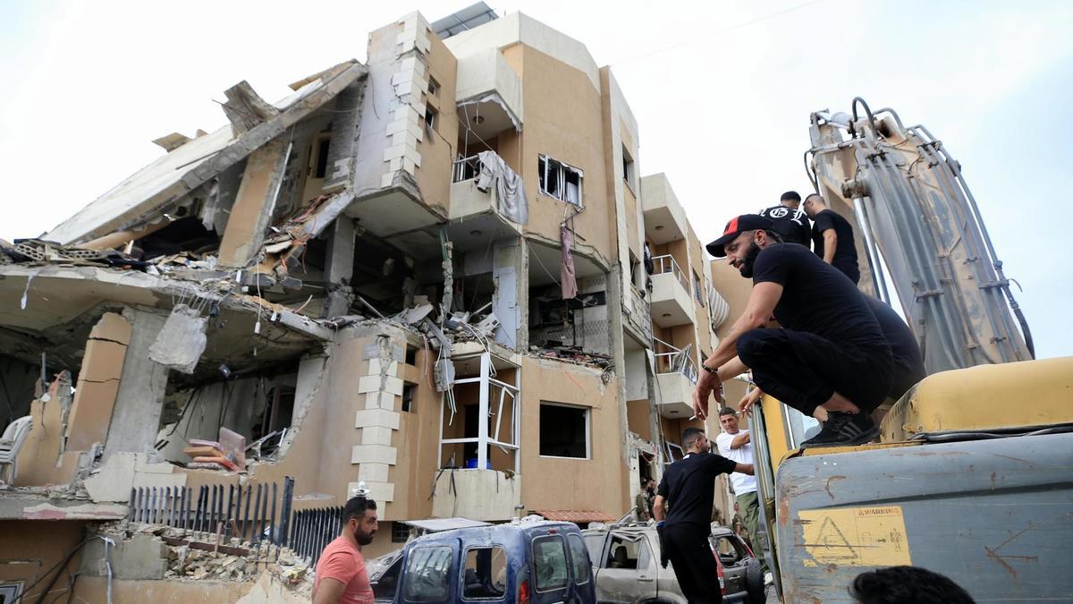 Varias personas se reúnen en el lugar de un ataque militar israelí en Barja, al sur de Beirut.