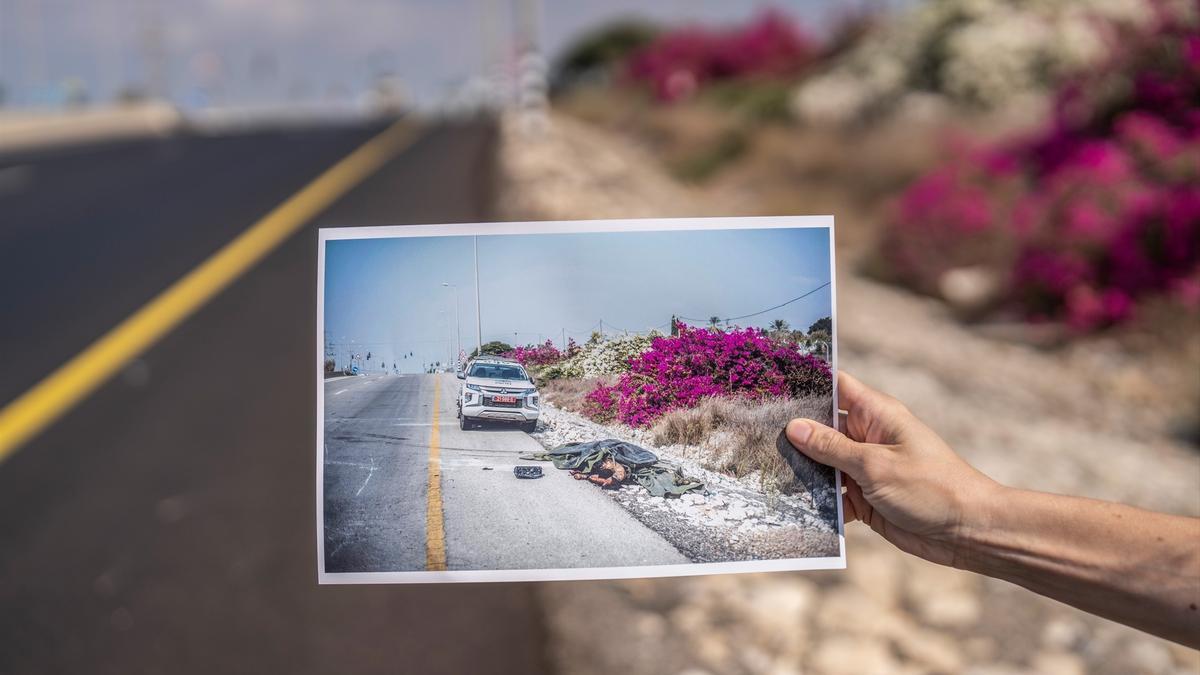 Una foto tomada en la localidad de Sderot el 7 de octubre de 2023 en la que se ve a un miliciano de Hamás muerto al lado de un coche de la Policía israelí.