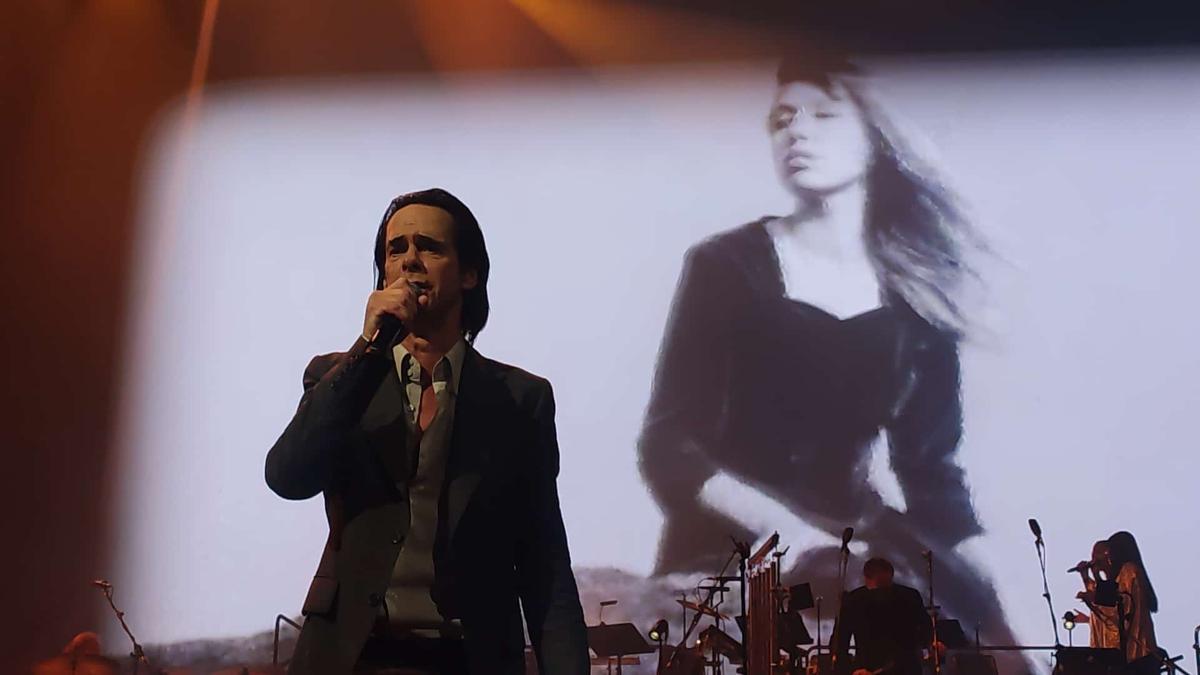 Nick Cave con una proyección de Anita Lane al fondo