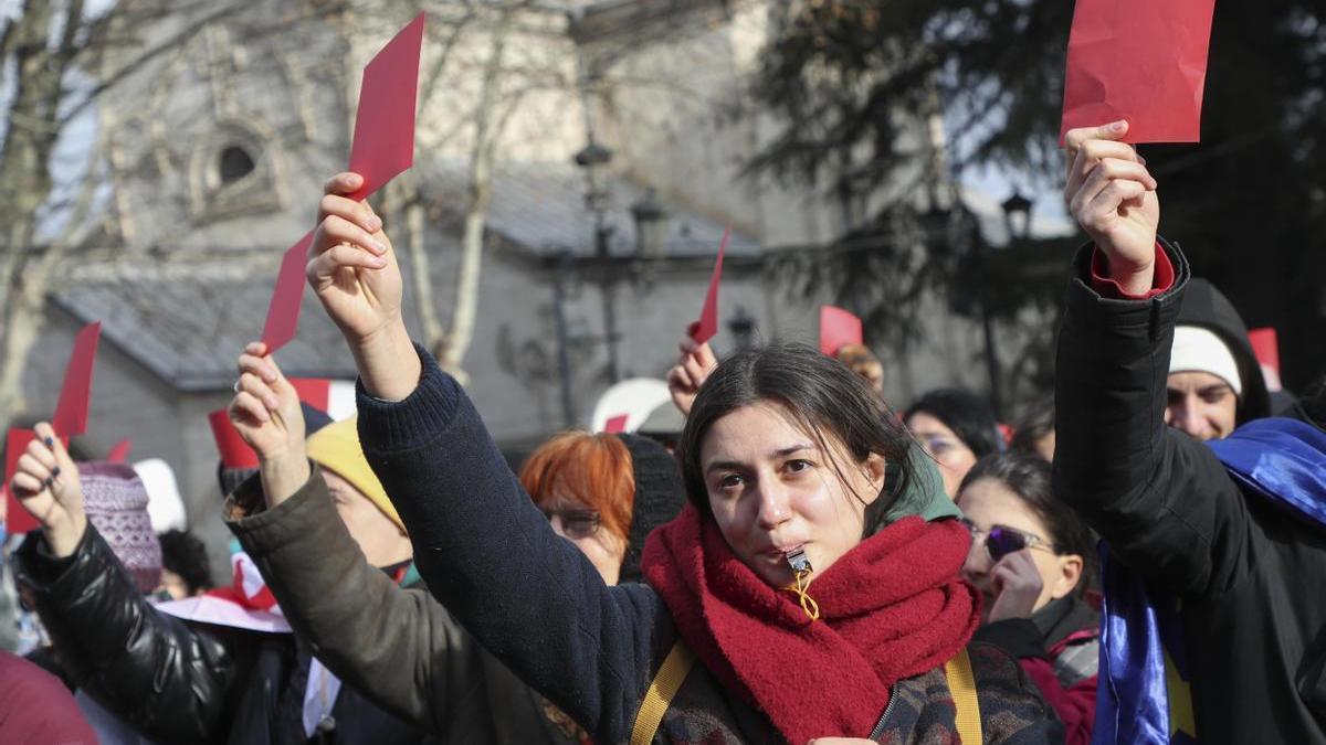 Varias personas protestan mostrando tarjetas rojas contra la investidura del nuevo presidente de Georgia.