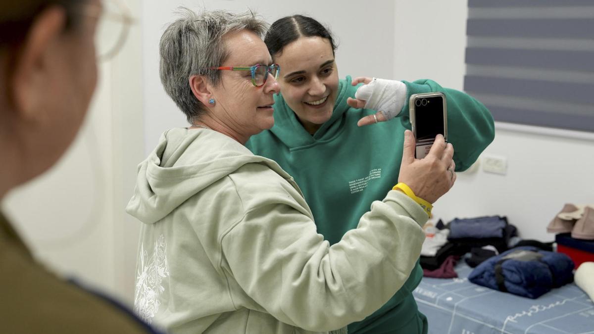 Emily Damari muestra su mano izquierda mientras mantiene una videollamada junto a su madre, Mandy, con su familia.