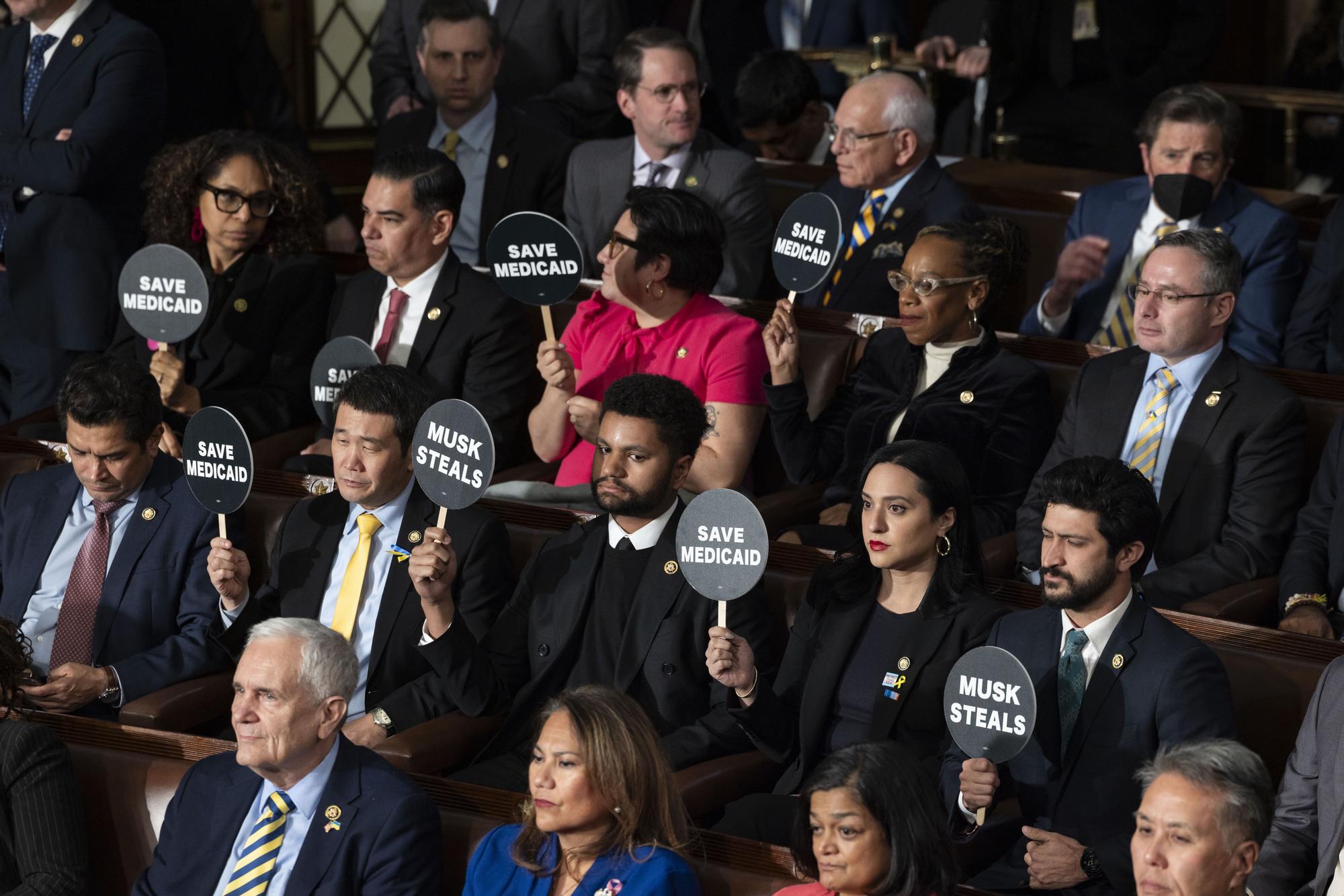 Los legisladores demócratas sostienen carteles durante el discurso de Trump.