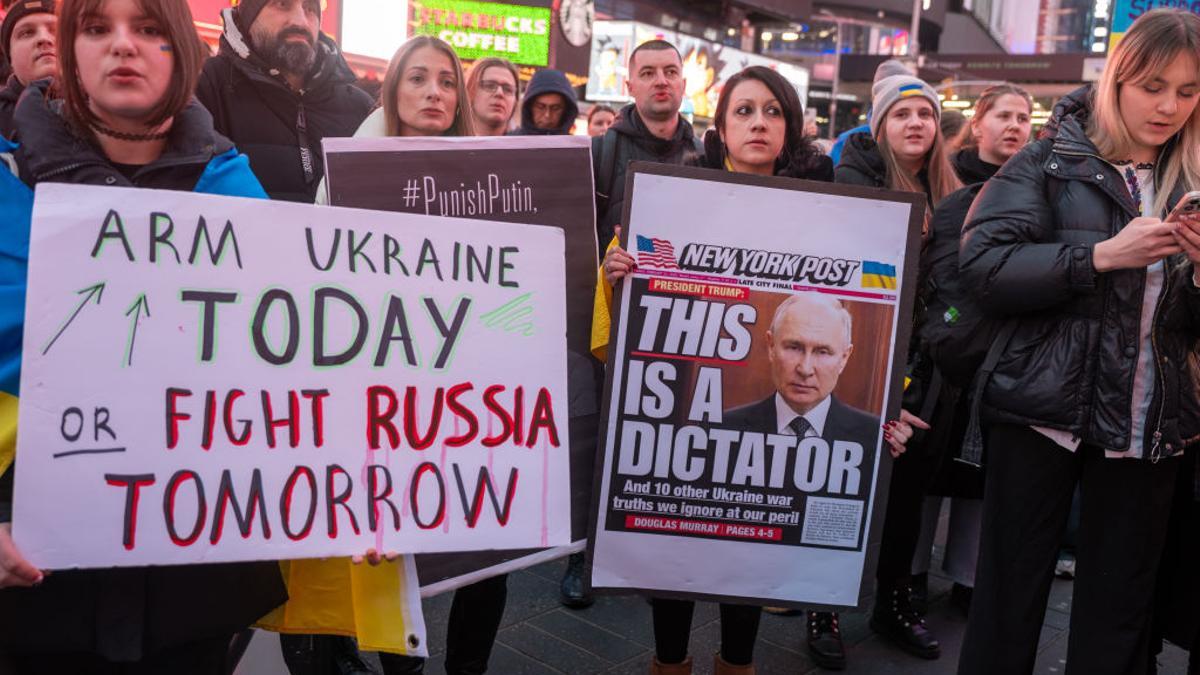 Un grupo de personas se manifiestan en apoyo a Ucrania el 24 de febrero de 2025 en Times Square, Nueva York, mostrando una portada del 'New York Post' crítica con Trump.